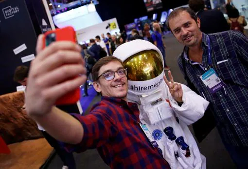 Dos visitantes se fotografían con una persona vestida de astronauta en la Web Summit