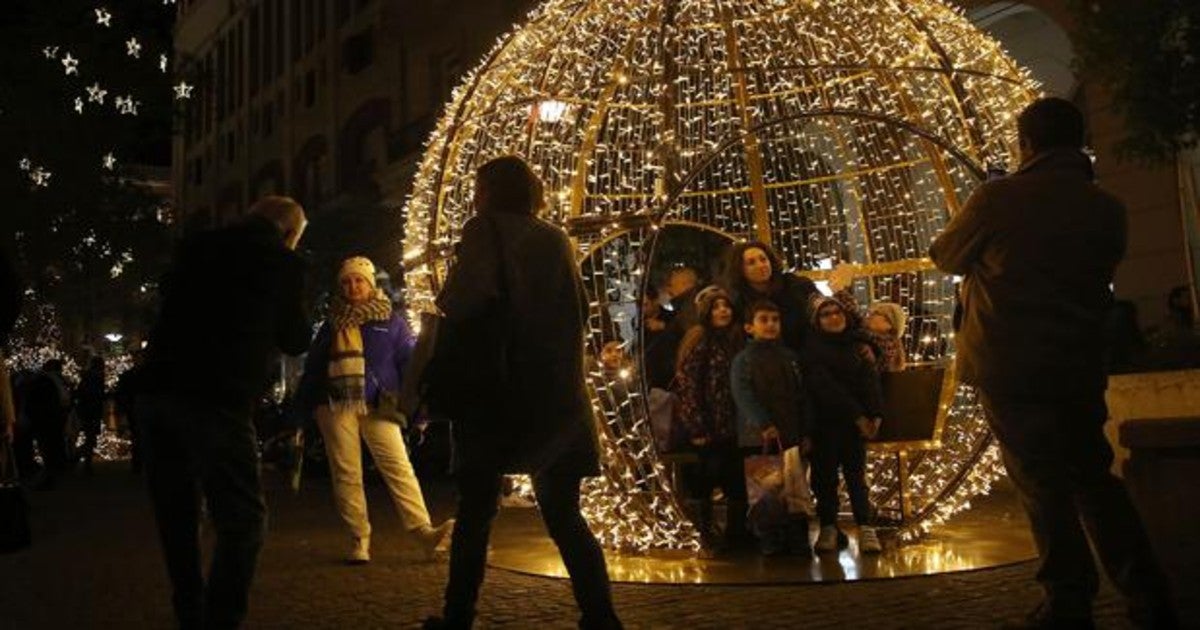 Familias griegas se hacen fotos delante de lso adornos de Navidad en Atenas