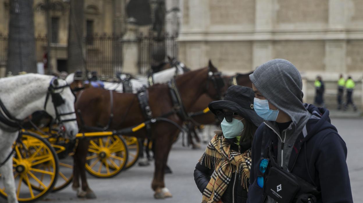 Dos turistas con mascarillas pasean por el centro de Sevilla