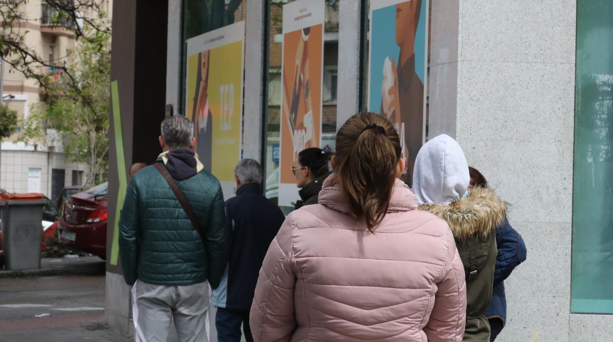 Personas hacen cola frente a una oficina