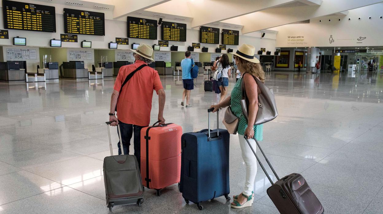 Varios turistas comprueban sus vuelos en el aeropuerto de Menorca