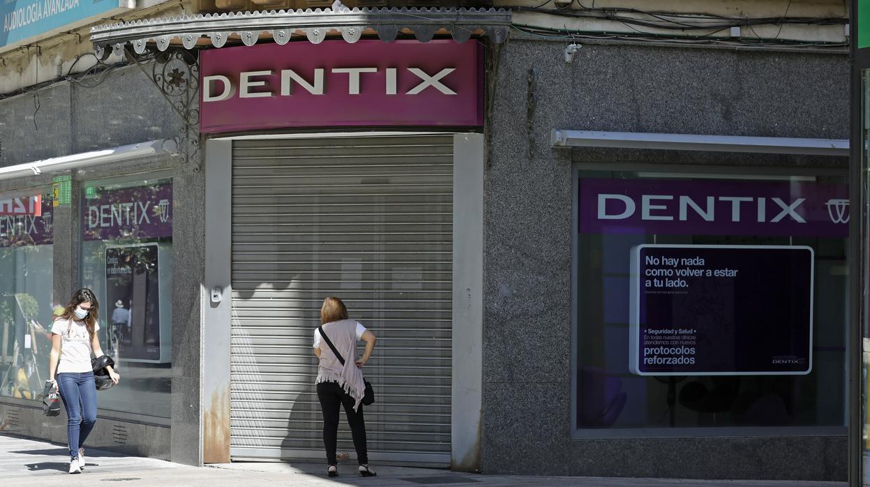 Una mujer ante la sede cerrada de Dentix