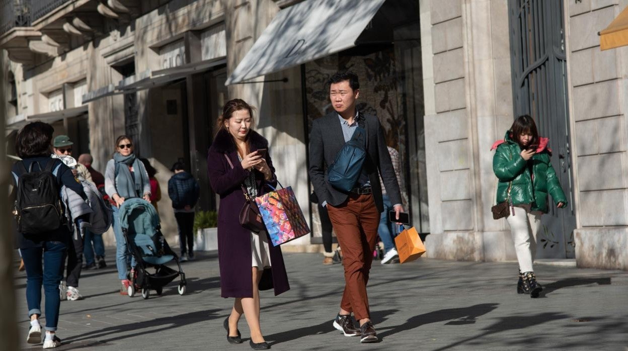 Turistas asiáticos con bolsas de tiendas de lujo en Barcelona