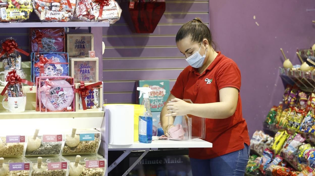 Una trabajadora de una tienda de golosinas de un centro comercial coloca la mercancía