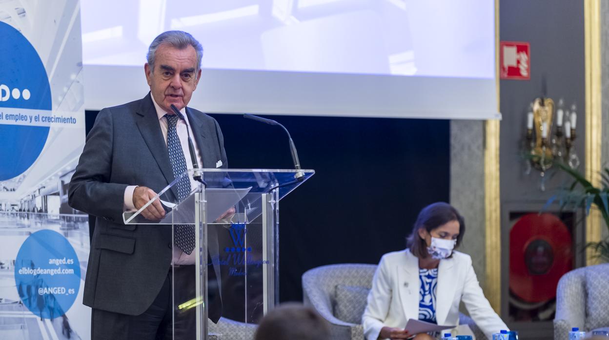 El presidente de Anged, Alfonso Merry del Val, y, de fondo, la ministra de Industria, Comercio y Turismo, Reyes Maeoto