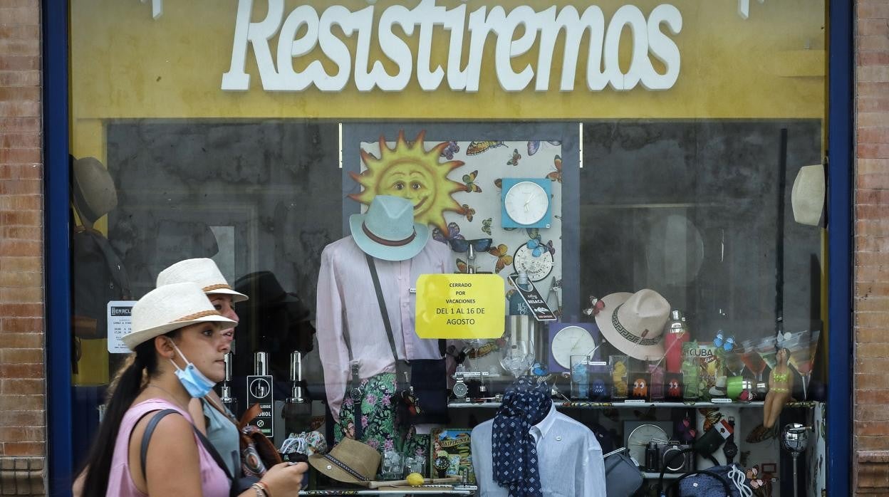 Dos viandantes pasan ante el escaparate de un comercio de la Cuesta del Rosario de Sevilla