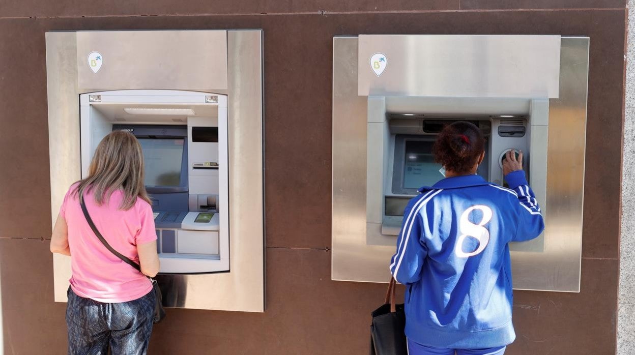 Dos personas sacando dinero en cajeros de Madrid