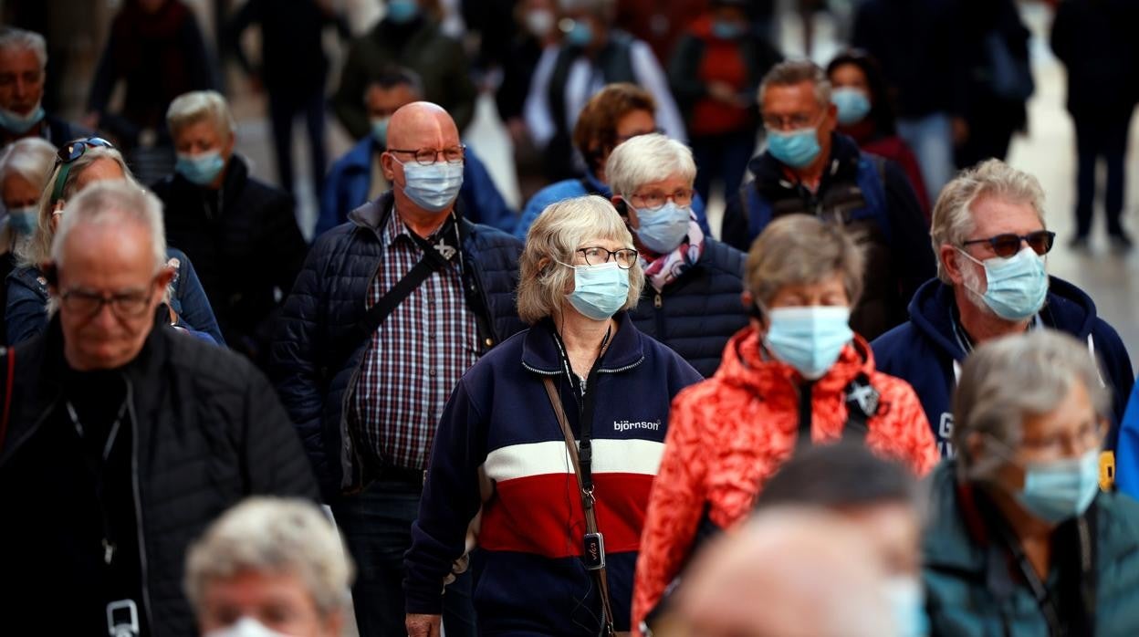 Grupo de personas con mascarillas por la calle