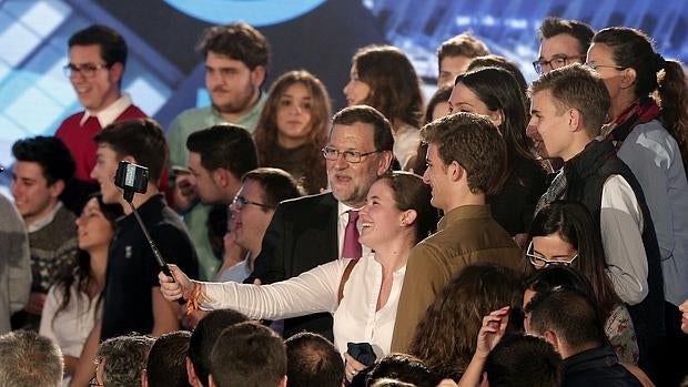 El candidato del Partido Popular a la presidencia del gobierno, Matriano Rajoy, se toma una fotografía con un grupo de jovenes al finalizar un mitin en Valencia