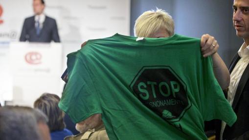 Una activista de la PAH muestra una camiseta alusiva a los deshaucios durante intervención de Rajoy