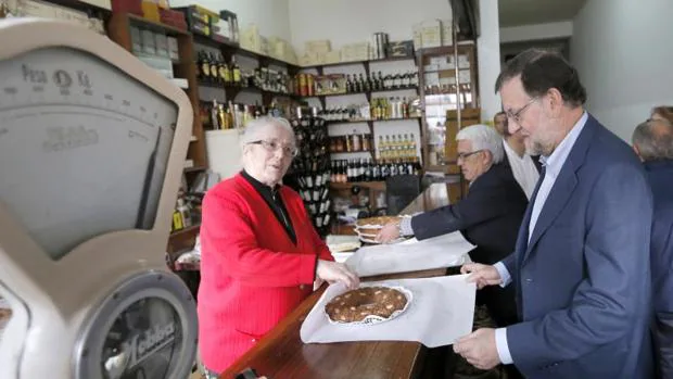 Rajoy recibe una tarta que le regala la dueña de una tienda en agradecimiento por su visita