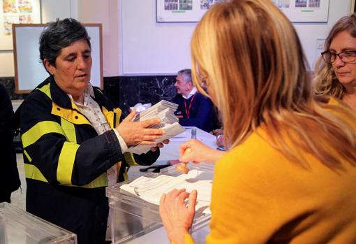 Una trabajadora de Correos entrega a la presidenta de una mesa electoral