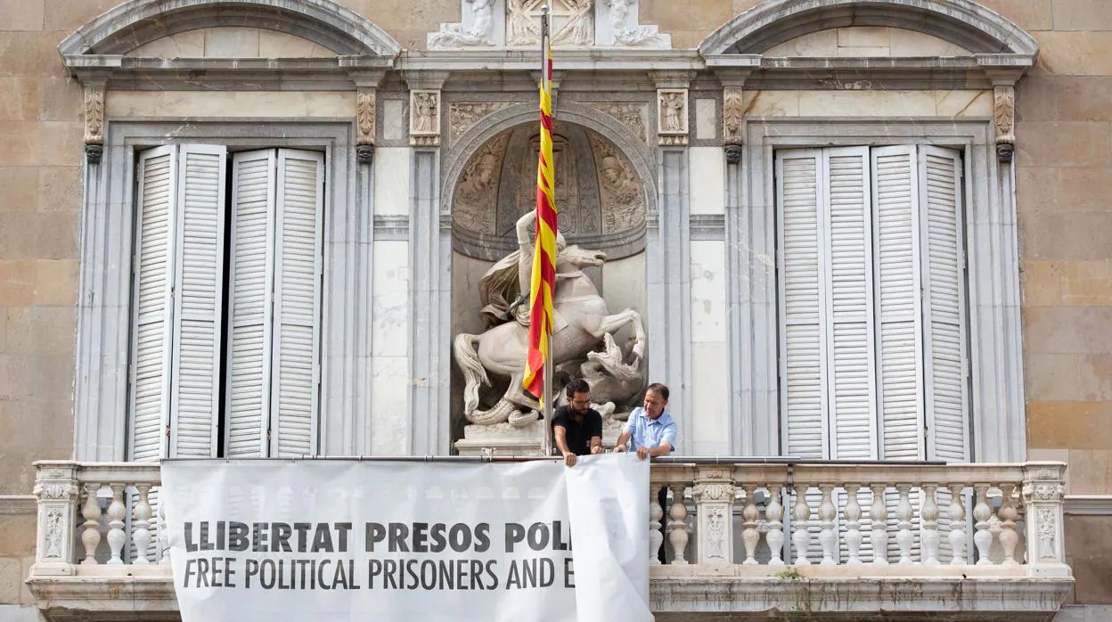 Momento en que la pancarta con el lazo amarillo en honor a los presos del «procés» se retiró de la fachada de la Generalitat