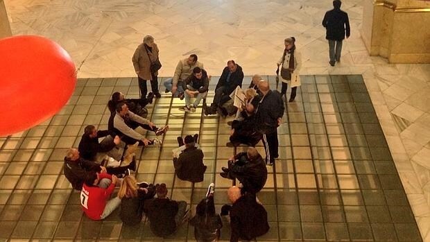 Los okupas neonazis, y algunas personas a las que buscan techo, sentados en el vestíbulo principal del Ayuntamiento de Madrid