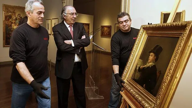 Dos operarios se disponen a colgar la obra Mariano Goya, más conocida como «Marianito», del pintor español Francisco de Goya, en presencia del presidente de la Fundación Ibercaja, Amado Franco