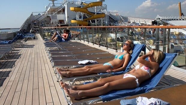 Cruceristas toman el sol en la terraza de un barco atracado en el puerto de Alicante