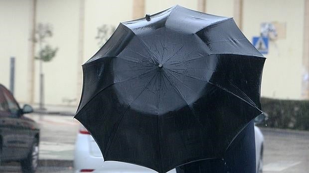 Un traseúnte se protege del viento y la lluvia en Ponferrada