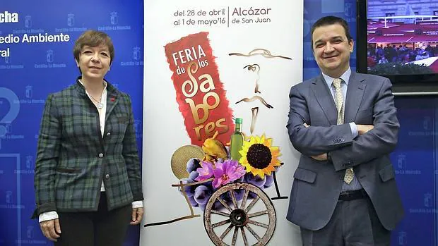 La alcaldesa de Alcázar, Rosa Melchor, y el consejero de Agricultura, Francisco Martínez, junto al cartel anunciador de la Feria durante la presentación de la misma en la Consejería