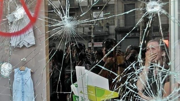 Una mujer llora tras ver los destrozos de su tienda tras una jornada de huelga