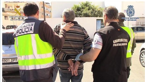 Agentes de la Policía Nacional y de la Guardia Civil conducen a uno de los detenidos