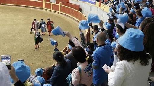 Los empleados del grupo Tiens agitan sus gorros en señal de aplauso a los toreros en Moralzarza