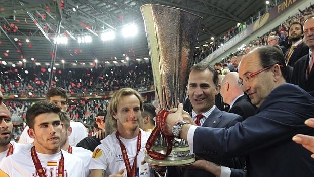 Don Felipe junto al presidente del Sevilla FC, José Castro, en mayo de 2014 entrega la copa de campeón de la Liga Europa al capitán del equipo andaluz Iván Rakitic, tras vencer al Benfica en Turín