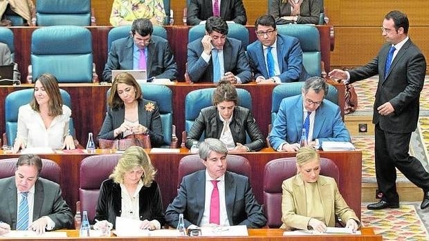 Daniel Ortiz pasa por detrás del escaño de Cristina Cifuentes, ayer, en la Asamblea