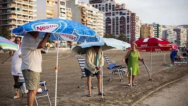 Unos bañistas colocan su sombrilla en Cullera (Valencia) en una imagen de archivo