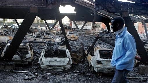 Un joven pasea al lado de coches quemados en las afueras de París en 2005