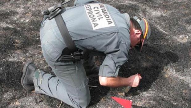 Un agente de la Guardia Civil, durante la investigación en la zona del incendio