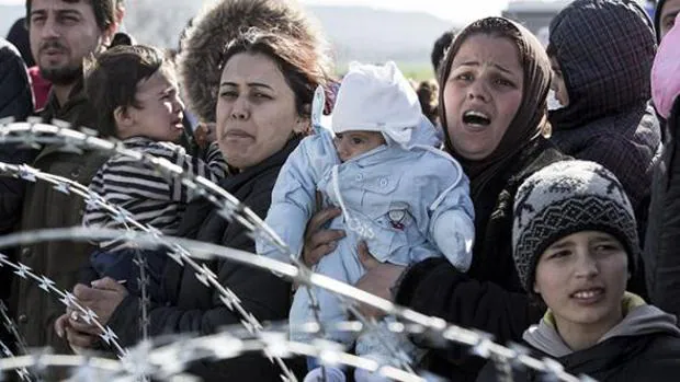 Varias madres sirias aguardan al otro lado de la frontera con sus hijos en brazos