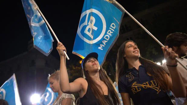 Dos simpatizantes del PP ondean la bandera del partido, anoche, en la celebración de Génova