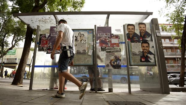 Una marquesina de la avenida de la Albufera llena de carteles de Unidos Podemos