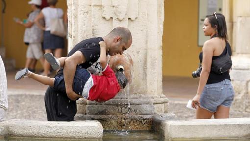 Un hombre echa agua a su hijo para refrescarlo