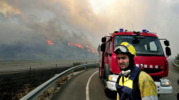 Un efectivo del cuerpo de bomberos observa en la AP-7 las llamas de un incendio en Jonqueras (Gerona)