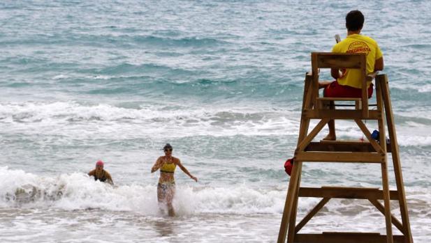 Un socorrista y dos bañistas en una playa de la Costa Blanca.