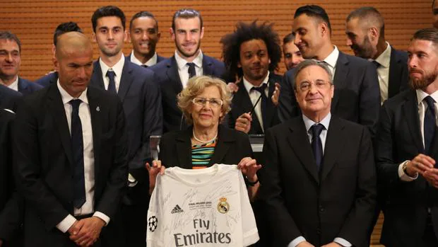 Manuela Carmena posa con una camiseta del Real Madrid junto a Florentino Pérez y la plantilla, tras ganas la Undécima