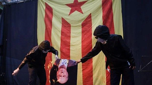 Dos encapuchados preden fuego a una imagen de Don Juan Carlos durante la Diada de 2011