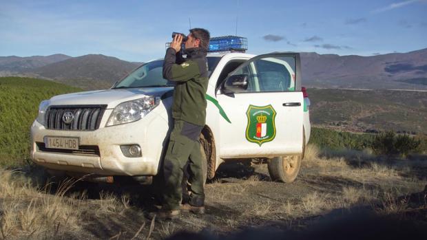 Un agente medioambiental junto a un vehículo oficial con los rotativos instalados