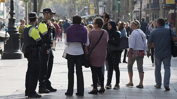 Un grupo de turistas junto a unos policías en la Rambla de Barcelona
