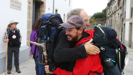 Dos peregrinos se abrazan tras terminar el Camino en Santiago