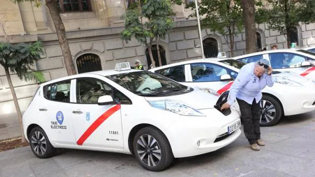 Una conductora uniformada muestra el punto donde se enchufan a la red los nuevos taxis eléctricos