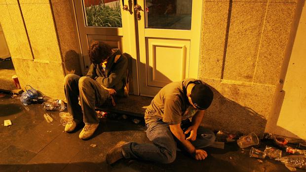 Dos jóvenes, rodeados de los restos de un botellón en una calle de La Coruña