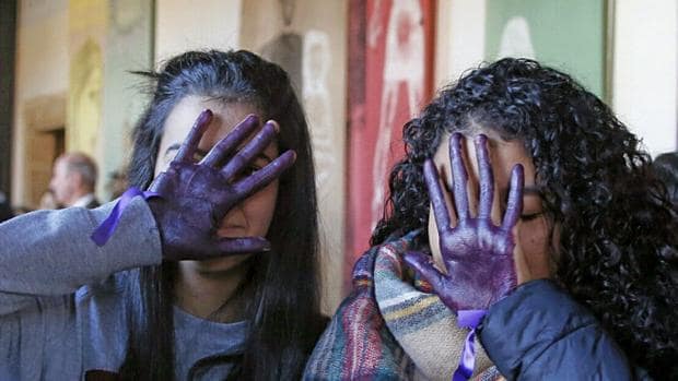 Dos adolescentes gallegas se cubren el rostro con las manos pintadas de violeta durante un acto por el 25 de noviembre en un instituto