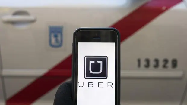 Un móvil con la aplicación Uber delante de un taxi