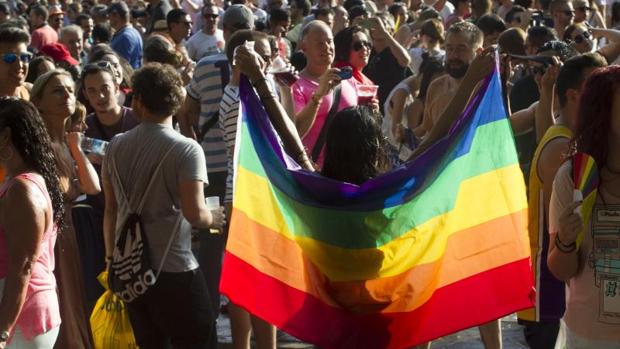 Una mujer sosiene una bandera arcoíris durante las fiestas del Orgullo Gay
