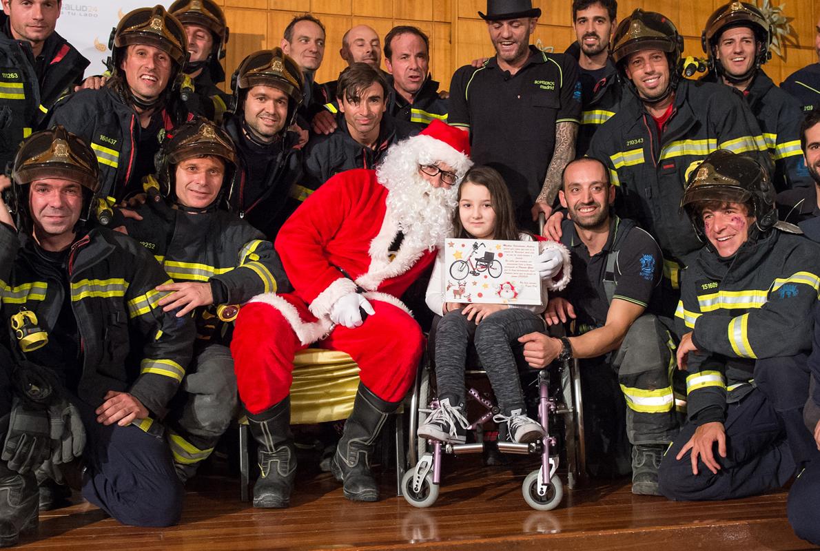 Papa Noel y los bomberos del Ayuntamiento de Madrid posan con una pequeña ingresada en el hospital