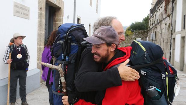 Dos peregrinos se abrazan tras terminar el Camino de Santiago