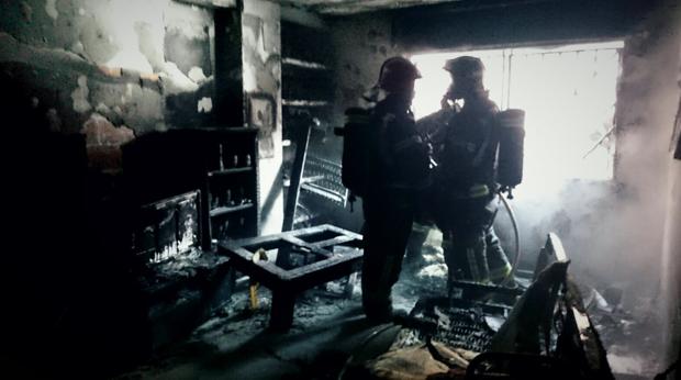 Dos bomberos en el interior de una de las viviendas calcinadas por el humo