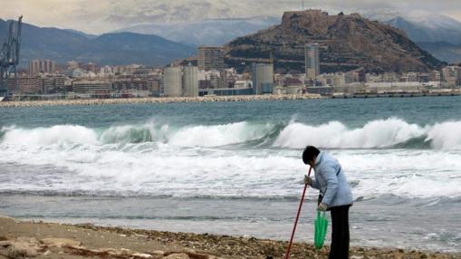 Mar revuelta por el temporal en la ciudad de Alicante, con la nieve al fondo en las montañas